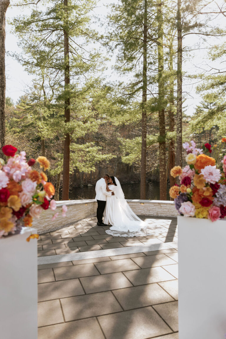 Bride and groom sharing a kiss at the outdoor ceremony space at Lakeview Pavilion, a luxury waterfront wedding venue in Foxborough, Massachusetts.