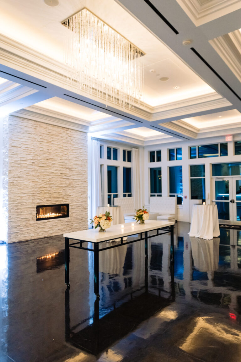 Elegant Lakeside lounge at Lakeview Pavilion in Foxborough, Massachusetts featuring crystal chandeliers, a modern fireplace, floor-to-ceiling windows, and spacious luxury wedding reception space.