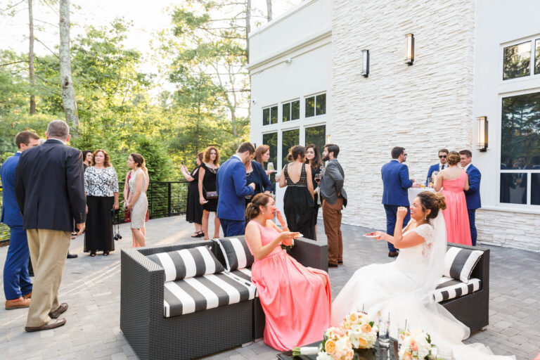 Guests enjoying cocktail hour on the outdoor terrace at Lakeview Pavilion in Foxborough, Massachusetts, featuring lounge seating, waterfront views, and modern wedding venue architecture.