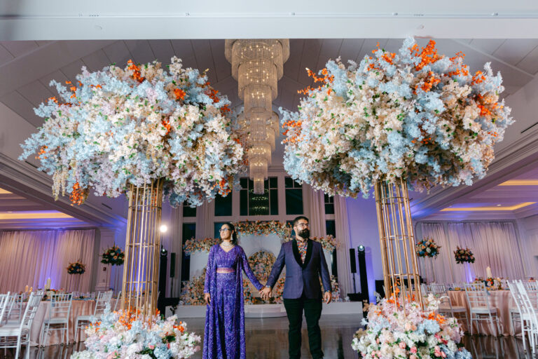 Couple standing beneath elegant floral installations during their wedding reception in the Lakeview Ballroom at Lakeview Pavilion in Foxborough, Massachusetts.