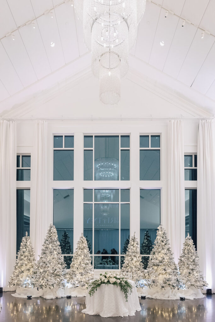 Elegant winter wedding reception at Lakeview Pavilion featuring sparkling Christmas trees and floor-to-ceiling windows in Foxborough, Massachusetts.