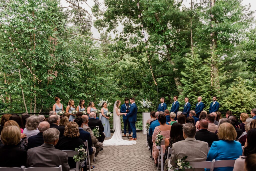 Outdoor wedding ceremony on the private terrace beside the Lakeside Ballroom at Lakeview Pavilion in Foxborough, Massachusetts, surrounded by lush woodland views.