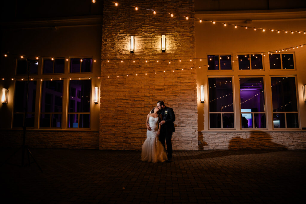 Bride and groom sharing a romantic evening portrait on the outdoor terrace outside the Lakeside Ballroom at Lakeview Pavilion in Foxborough, Massachusetts.