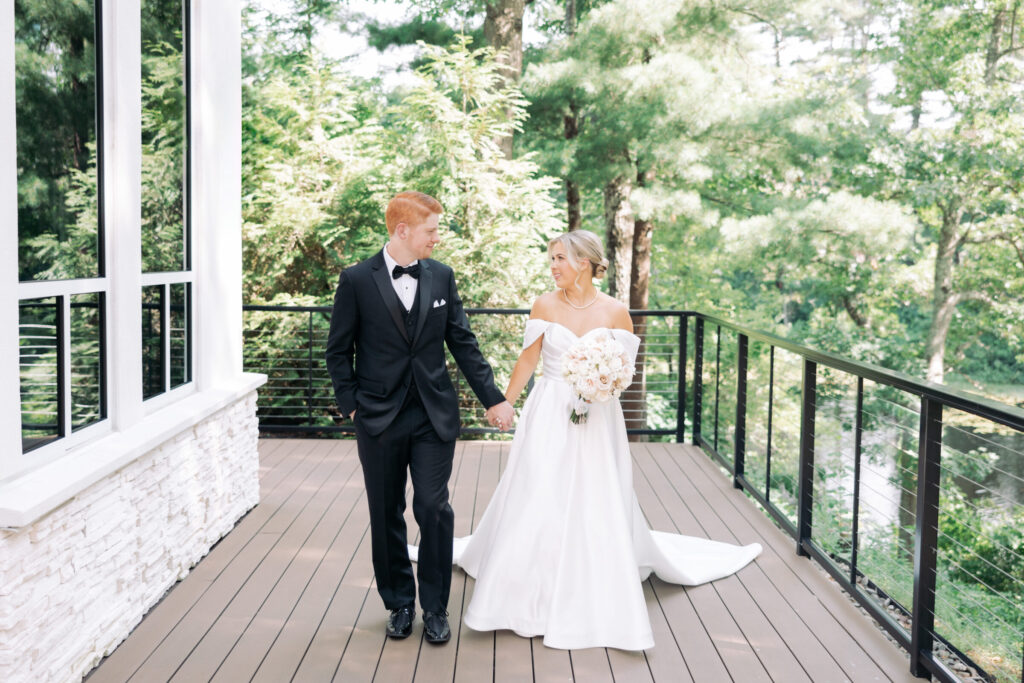 Bride and groom walking hand in hand on the private terrace outside the Lakeside Ballroom at Lakeview Pavilion in Foxborough, Massachusetts.