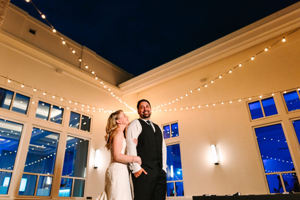 Bride and groom enjoying an evening on the private outdoor terrace outside the Lakeside Ballroom with café lights at Lakeview Pavilion in Foxborough, Massachusetts.